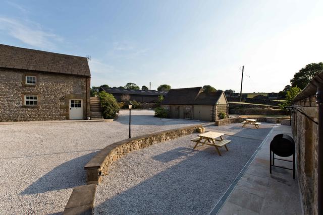Patio area with picnic tables and BBQ at the front of the Barn